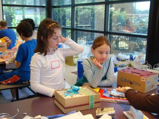 Two girls wrapping gifts at a sunlit table