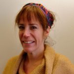 Headshot photo of a woman wearing a hairband and a sweater_