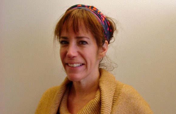 Headshot photo of a woman wearing a hairband and a sweater_