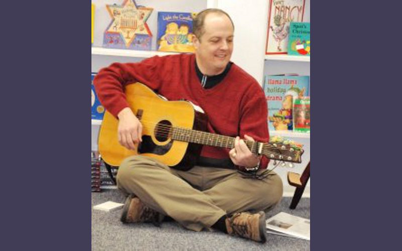 a man wearing a red sweater is playing a guitar