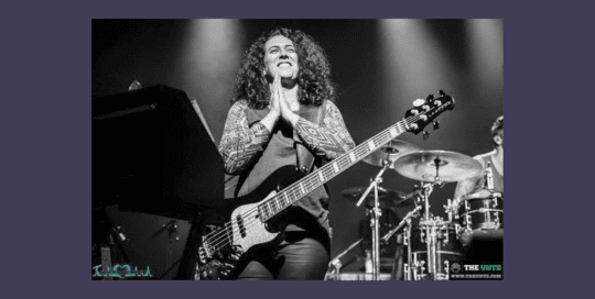 A woman on the stage with a guitar for a performance