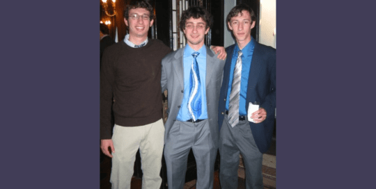 Three young boys at a party are posing for a photo_