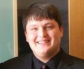 Headshot photo of a man in a black suit_