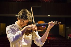 A Man in a White Shirt Is Playing a Violin